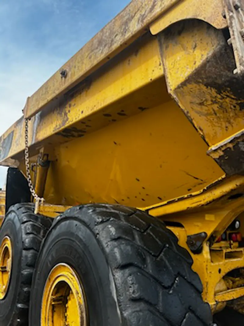 Mud packed into the suspension and bed of an articulated haul truck before washing