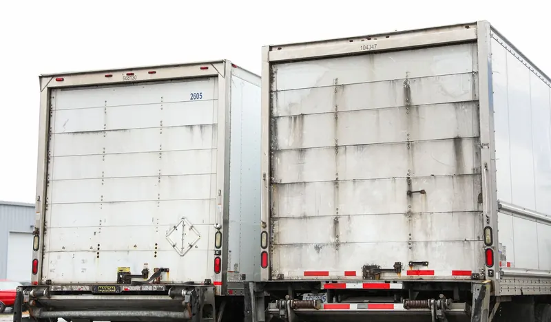 Two trailers side by side, one washed and one carrying a week of road film